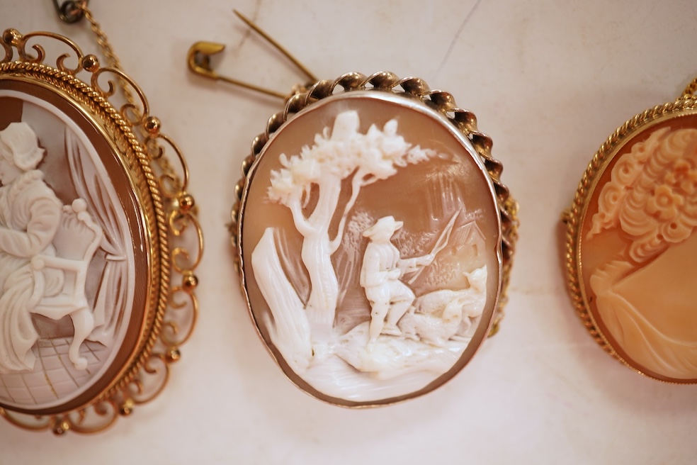 A collection of five cameo brooches, each of oval outline, set with a carved shell cameo, variously depicting three women in profile, a seated lady doing needlework, and a pastoral scene of a shepherd, longest 6.8cm, thr
